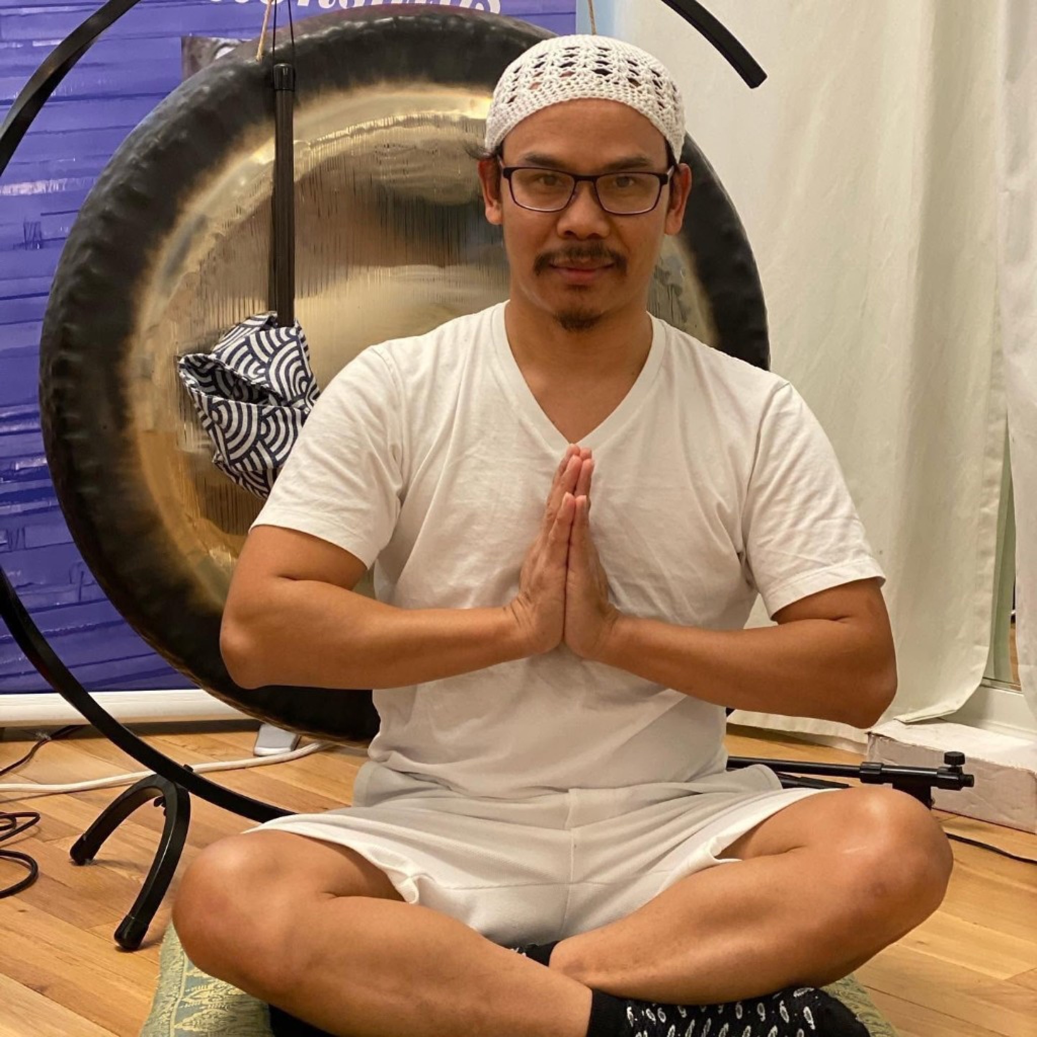Nakhone Keodara seated before a gong in Kundalini Yoga attire